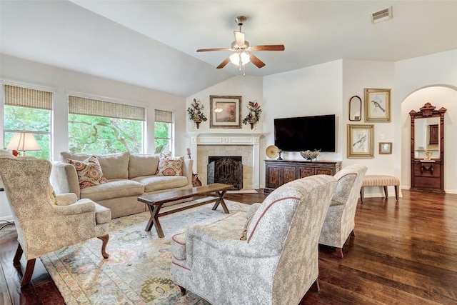 living area with a ceiling fan, dark wood-style flooring, a fireplace, vaulted ceiling, and baseboards
