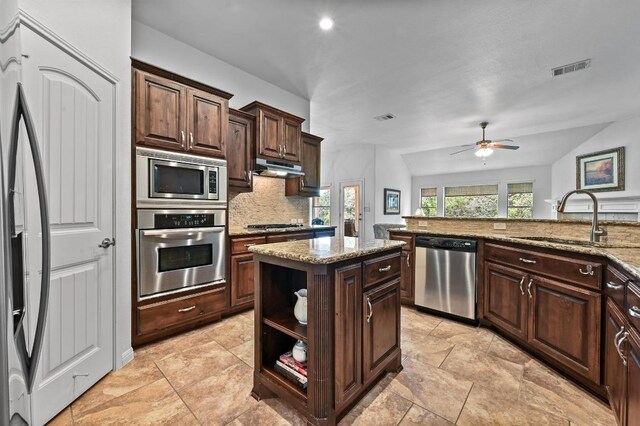 740 Harris Dr, Austin, TX 78737 - kitchen featuring appliances with stainless steel finishes, backsplash, under cabinet range hood, ceiling fan, and light stone counters
