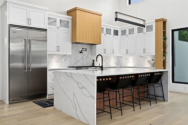 3305 Skylark Dr, Austin, TX 78757 - kitchen with built in refrigerator, light wood-style flooring, backsplash, white cabinetry, and light stone counters