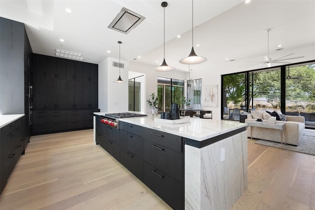 2502 Barhill Dr, Austin, TX 78704 - kitchen featuring modern cabinets, stainless steel gas stovetop, dark cabinetry, light wood-style floors, and a large island