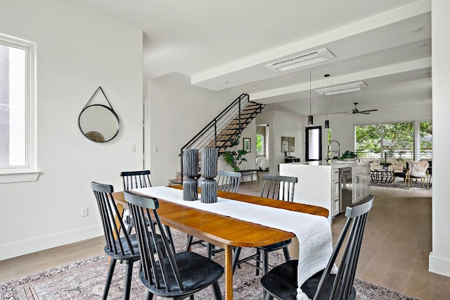dining space with wood finished floors, a ceiling fan, baseboards, and stairway