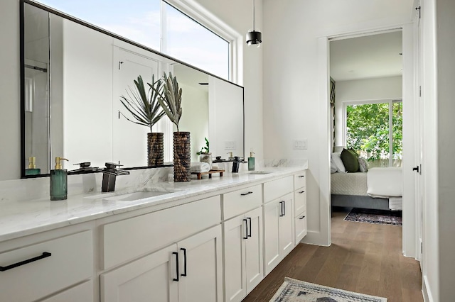 bathroom featuring wood finished floors, ensuite bath, and double vanity