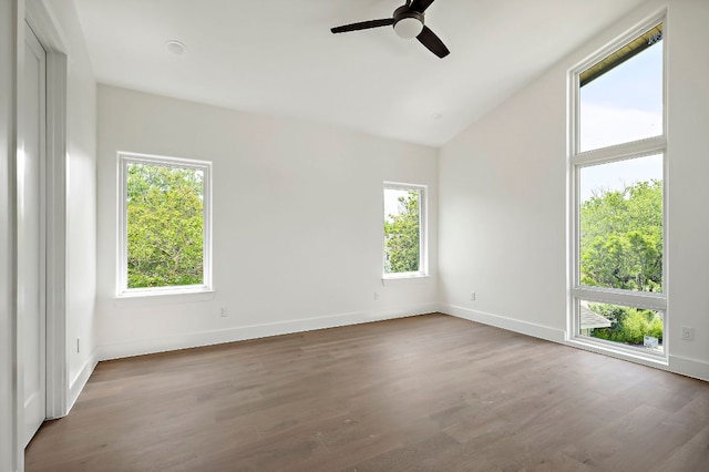 empty room with baseboards, a ceiling fan, wood finished floors, and vaulted ceiling