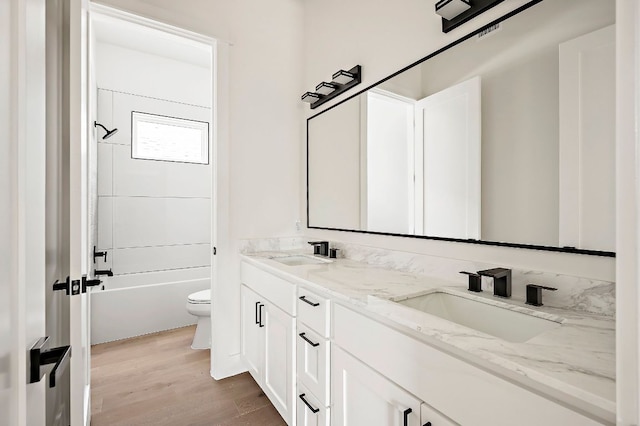 full bath featuring wood finished floors, double vanity, toilet, and bathtub / shower combination