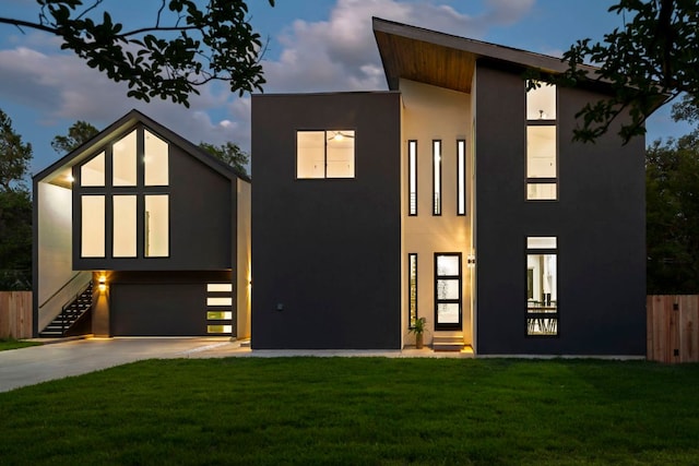 modern home with stucco siding, driveway, an attached garage, and stairway