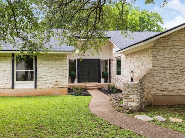 504 Ridgecrest Rd, Georgetown, TX 78628 - view of exterior entry featuring roof with shingles, a yard, and stone siding