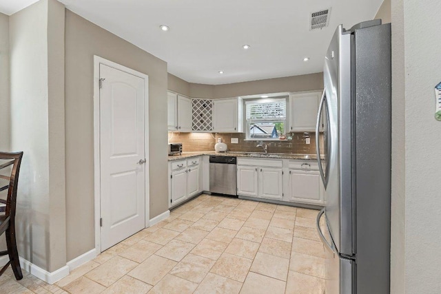 4806 Transit Cir, Austin, TX 78727 - kitchen featuring stainless steel appliances, a sink, decorative backsplash, white cabinetry, and light stone countertops
