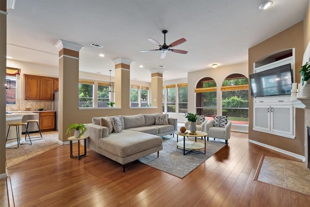 living room featuring decorative columns, a ceiling fan, light wood-type flooring, recessed lighting, and baseboards