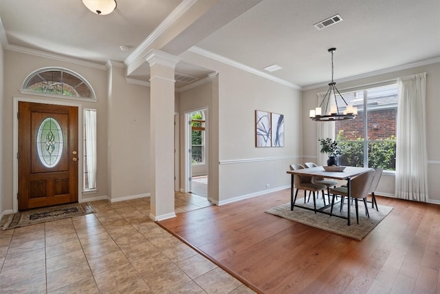 foyer with a chandelier, decorative columns, baseboards, crown molding, and light wood-style flooring