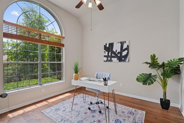 office with healthy amount of natural light, wood finished floors, baseboards, a ceiling fan, and vaulted ceiling