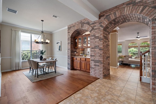 dining room with ceiling fan, a chandelier, arched walkways, baseboards, and crown molding