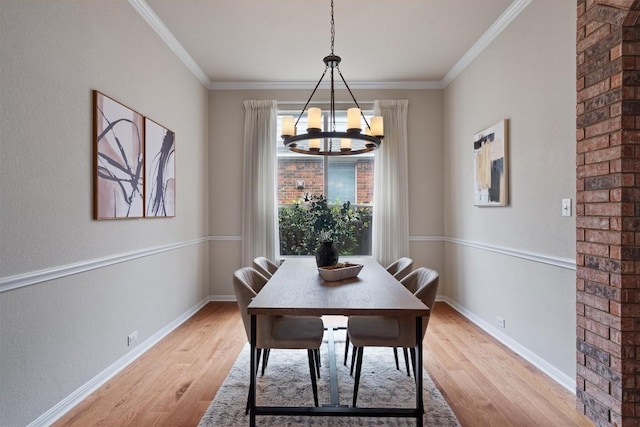 dining area with light wood-type flooring, a chandelier, baseboards, and crown molding