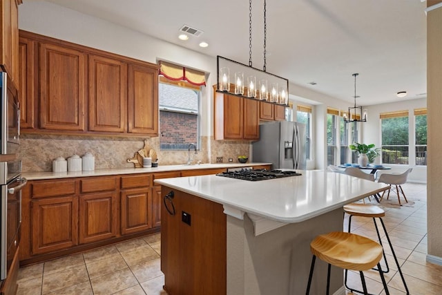 kitchen with appliances with stainless steel finishes, brown cabinets, a breakfast bar area, decorative backsplash, and recessed lighting