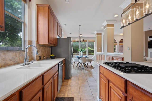 kitchen with stainless steel appliances, a sink, brown cabinetry, a chandelier, and recessed lighting