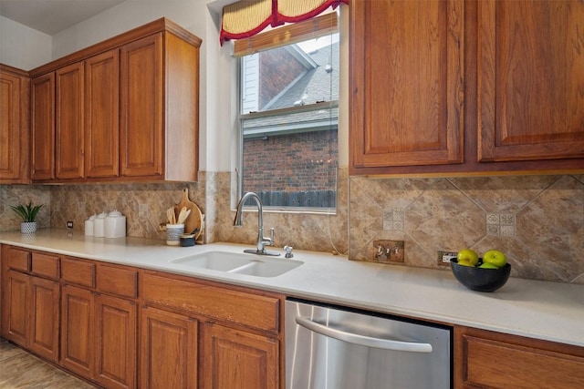 kitchen with stainless steel dishwasher, a sink, brown cabinetry, and light countertops