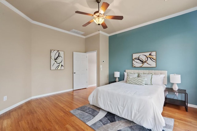 bedroom with wood finished floors, crown molding, baseboards, and a ceiling fan