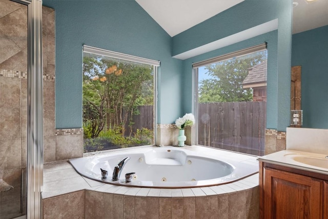 bathroom featuring a whirlpool tub, lofted ceiling, and vanity