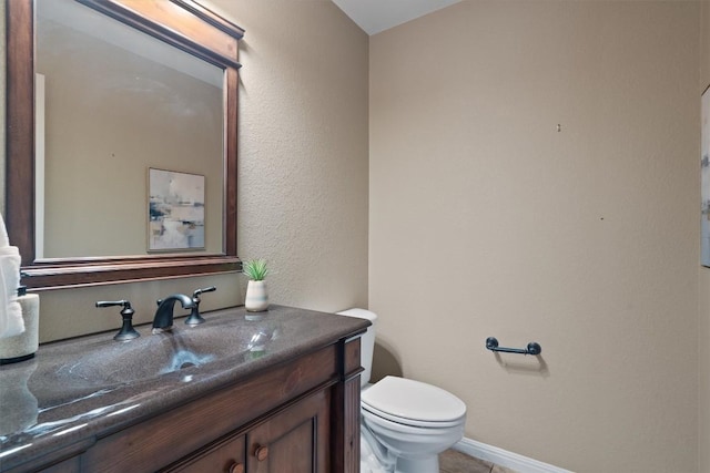 bathroom featuring toilet, vanity, and baseboards