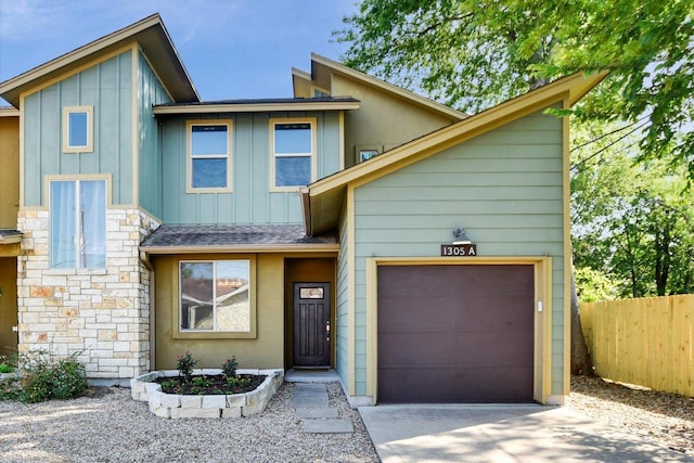 view of front of house with fence, board and batten siding, a garage, concrete driveway, and stone siding