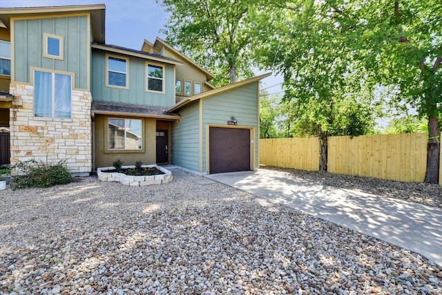 view of front of property with board and batten siding, concrete driveway, an attached garage, and fence