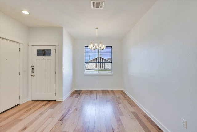 foyer entrance featuring light wood-style floors, a chandelier, and baseboards