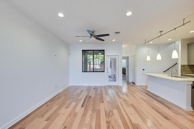 unfurnished living room featuring a sink, recessed lighting, light wood finished floors, ceiling fan, and baseboards