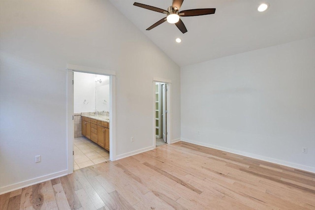 unfurnished bedroom featuring light wood-style flooring, high vaulted ceiling, recessed lighting, a sink, and baseboards