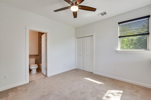 unfurnished bedroom with carpet flooring, a closet, ensuite bath, baseboards, and ceiling fan