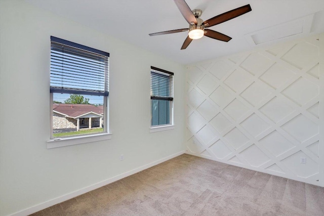 spare room featuring carpet, a ceiling fan, baseboards, and attic access