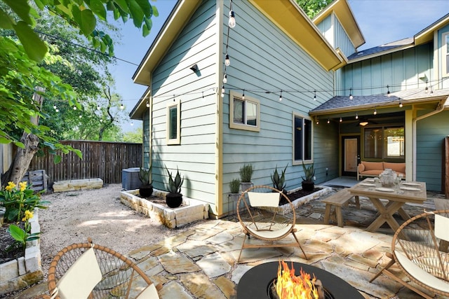rear view of property with a patio, an outdoor living space with a fire pit, a fenced backyard, central air condition unit, and board and batten siding