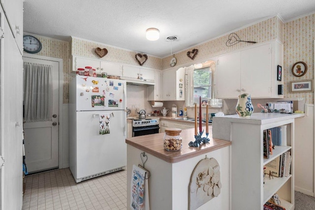 3108 W Terrace Dr, Austin, TX 78757 - kitchen with freestanding refrigerator, wallpapered walls, electric stove, crown molding, and white cabinetry
