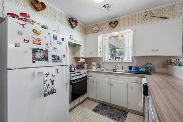 3108 W Terrace Dr, Austin, TX 78757 - kitchen featuring freestanding refrigerator, electric range oven, a sink, wallpapered walls, and white cabinets