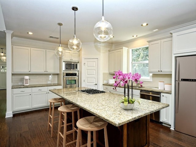 18 N Peak Rd, West Lake Hills, TX 78746 - kitchen with appliances with stainless steel finishes, decorative backsplash, a kitchen island, crown molding, and dark wood finished floors