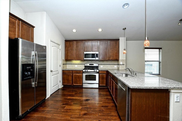 15628 Interlachen Dr, Austin, TX 78717 - kitchen featuring appliances with stainless steel finishes, a peninsula, dark wood-style flooring, light stone countertops, and backsplash