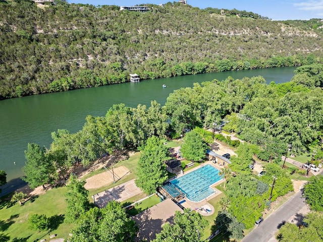 aerial overview of property's location featuring a nearby body of water, a heavily wooded area, and a pool