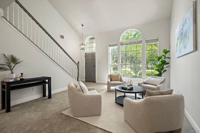 living area with stairway, baseboards, and a towering ceiling