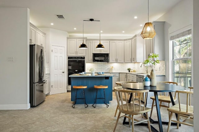 kitchen featuring black appliances, a center island, tasteful backsplash, a breakfast bar area, and decorative light fixtures