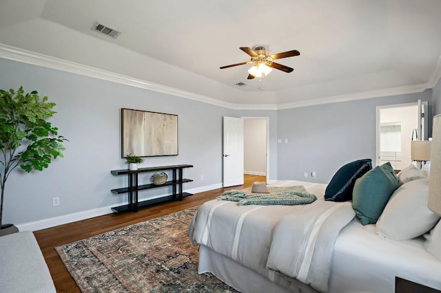 bedroom with a tray ceiling, wood finished floors, baseboards, crown molding, and a ceiling fan