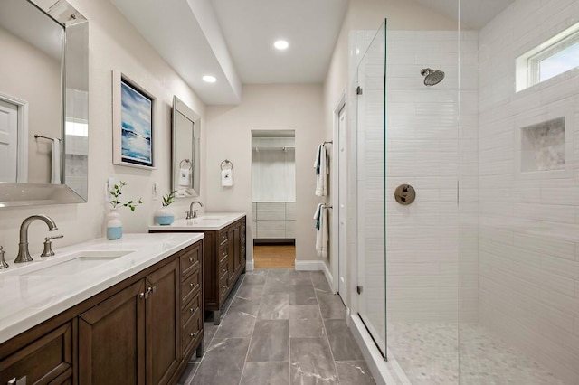 full bath with a tile shower, recessed lighting, and two vanities