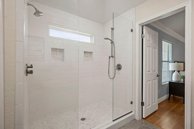 bathroom with crown molding, a tile shower, and baseboards