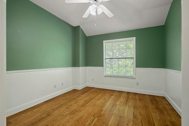 empty room featuring lofted ceiling, wood finished floors, ceiling fan, and baseboards