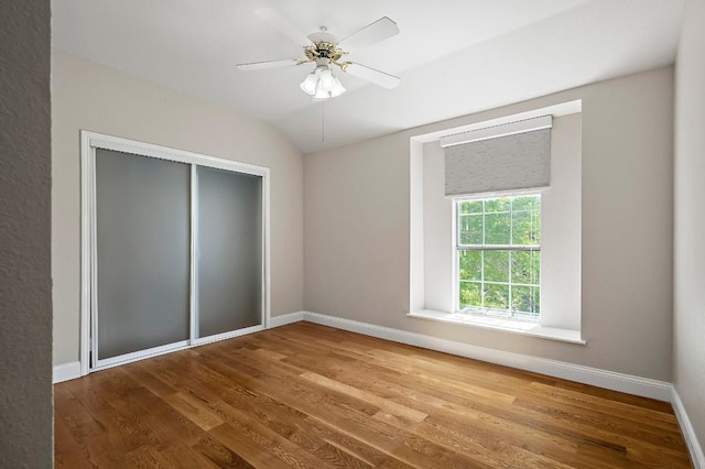 unfurnished bedroom with wood finished floors, baseboards, a closet, a ceiling fan, and lofted ceiling
