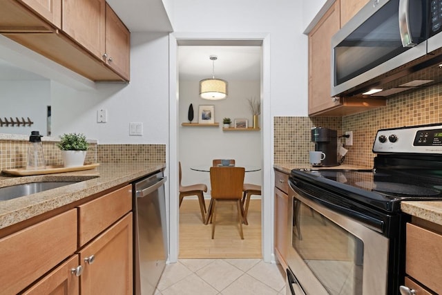 3204 Menchaca Rd Unit 716, Austin, TX 78704 - kitchen featuring appliances with stainless steel finishes, backsplash, light tile patterned floors, light stone countertops, and brown cabinetry