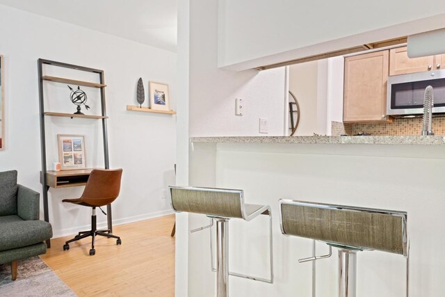 3204 Menchaca Rd Unit 716, Austin, TX 78704 - kitchen featuring stainless steel microwave, light wood finished floors, light brown cabinets, decorative backsplash, and light countertops
