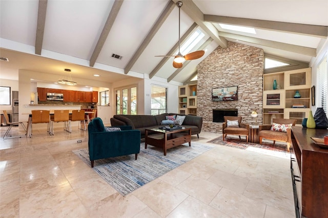 living room with a fireplace, plenty of natural light, ceiling fan, beam ceiling, and built in features