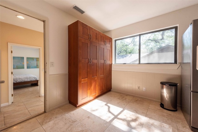 unfurnished bedroom with a wainscoted wall and a closet