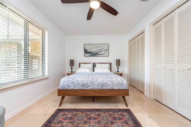 bedroom with multiple closets, baseboards, and ceiling fan