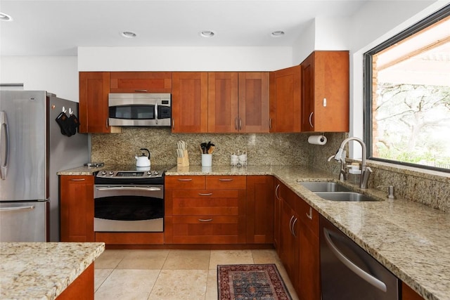 11532 Spicewood Pkwy, Austin, TX 78750 - kitchen featuring stainless steel appliances, decorative backsplash, light stone counters, and brown cabinetry