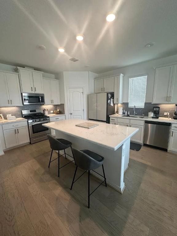 2050 Egret Ave, New Braunfels, TX 78132 - kitchen with stainless steel appliances, backsplash, a kitchen bar, a kitchen island, and white cabinetry