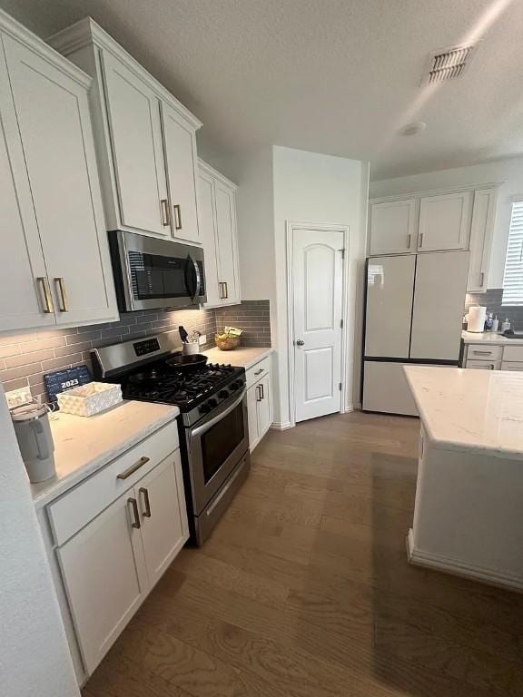 2050 Egret Ave, New Braunfels, TX 78132 - kitchen with stainless steel appliances, dark wood-type flooring, white cabinetry, and backsplash